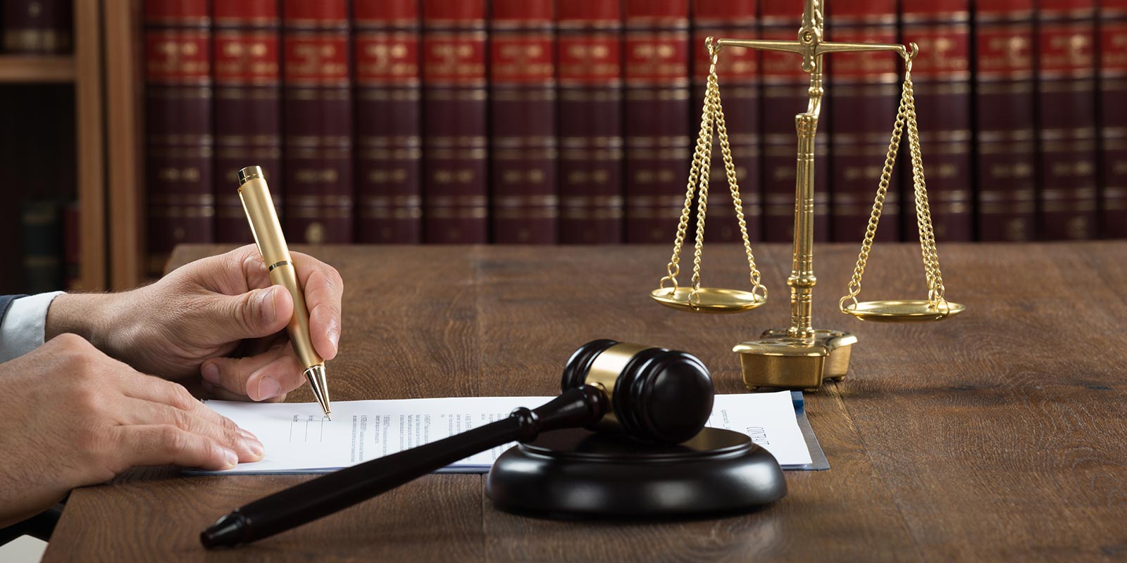 Desk with a gavel, the scales of justice, and books in the background