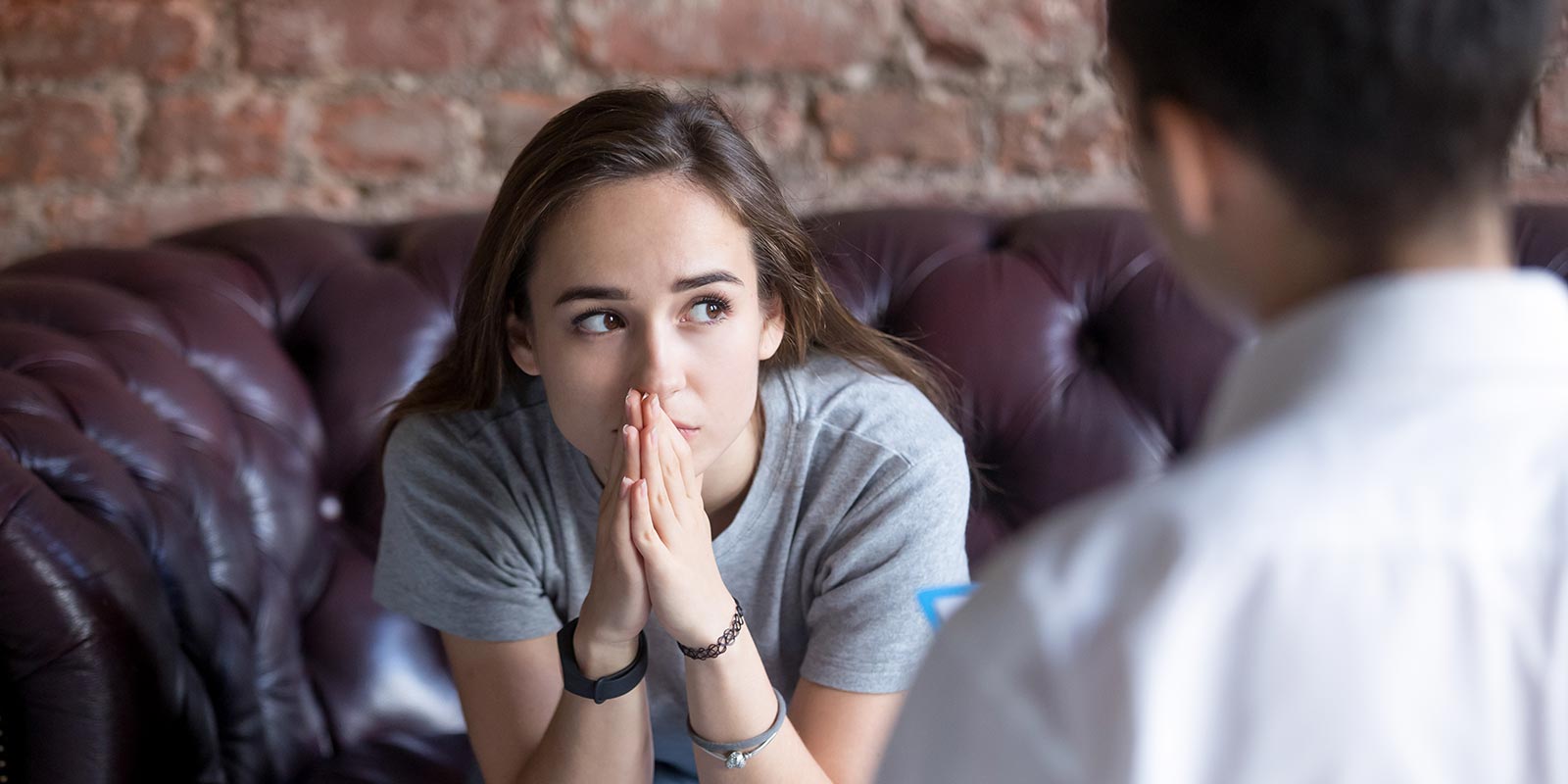 Young woman looking into the distance, while sitting on a therapist's couch