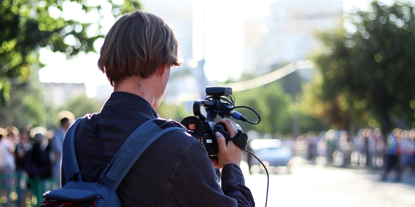 Camera man viewed from the back, shooting a scene