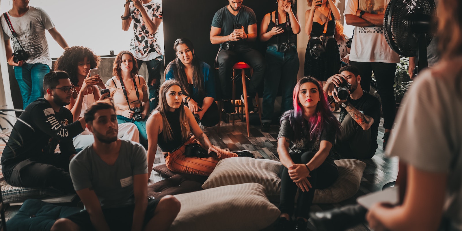 group of young people at an event, sitting on the floor watching a speaker