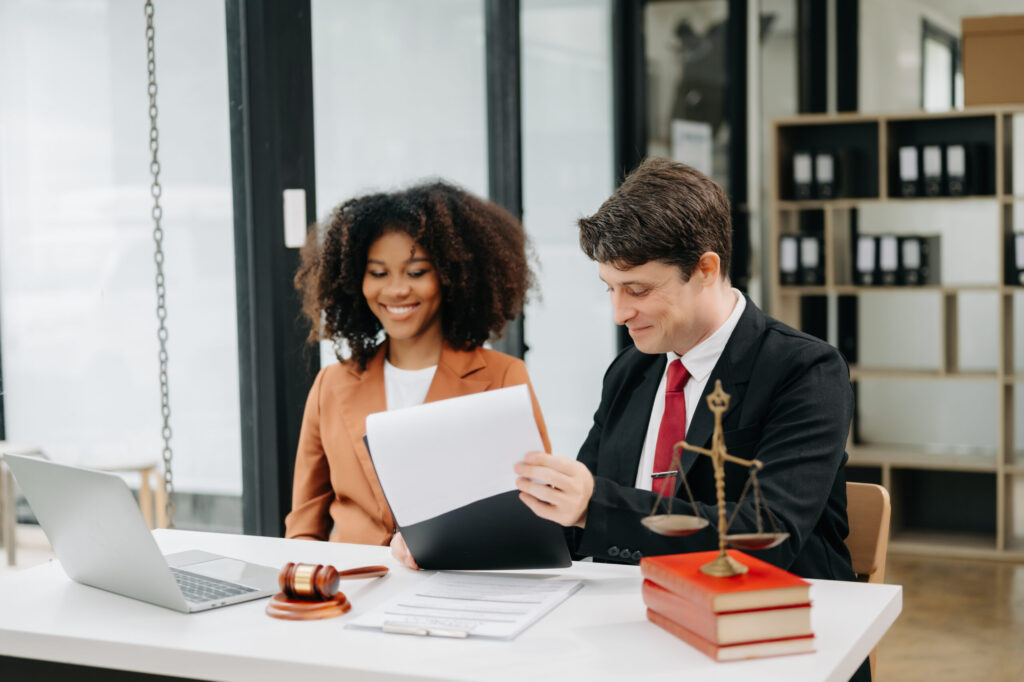 two young professionals sitting at a desk with books and the scales of justice