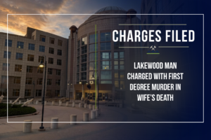 Graphic announcing criminal charges by the First Judicial District Attorney's Office. The background shows the Jefferson County Administration and Courts Building at dusk with a dark navy gradient overlay. At the top, the headline reads "Charges Filed."