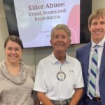 district attorney staff members stand smiling with an elderly male in front of a presentation screen